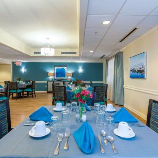 An elegantly set dining table with blue napkins and floral centerpiece in a well-lit dining room.