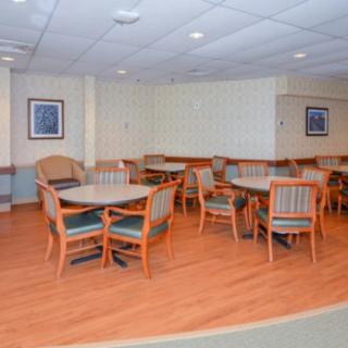 An empty dining area with round tables and chairs on a wooden floor.