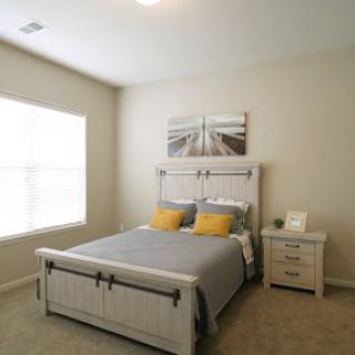 A cozy and modern bedroom featuring a comfortable bed with yellow accent pillows and a bright window.