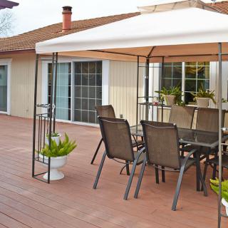 A cozy outdoor patio setup with a canopy covering a dining table and chairs on a wooden deck.