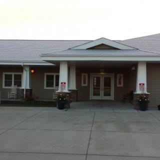 Front view of a building entrance with columns and decorative plants.