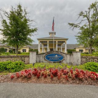 Entrance to a facility with a manicured garden and American flag.