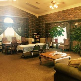 A cozy living room with comfortable seating, decorated with plants and natural light from large windows.