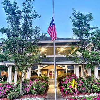 A beautifully landscaped building entrance with a prominently displayed American flag.