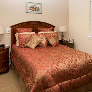 A cozy bedroom with a neatly made bed featuring a patterned comforter and decorative pillows, flanked by two nightstands with lamps.
