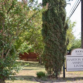 A sign surrounded by trees and landscaping in an outdoor setting.