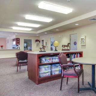 A quiet library space with chairs and bookshelves under bright ceiling lights.