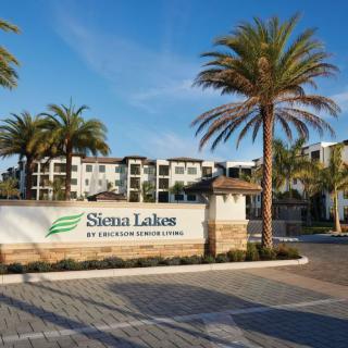 Entrance to Sienna Lakes apartment complex surrounded by palm trees.