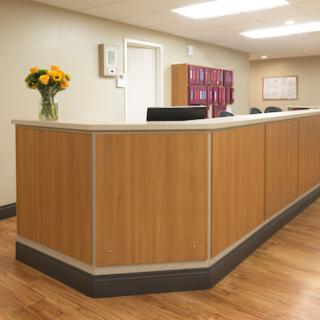 A modern reception desk in a well-lit office environment, adorned with a bouquet of flowers.