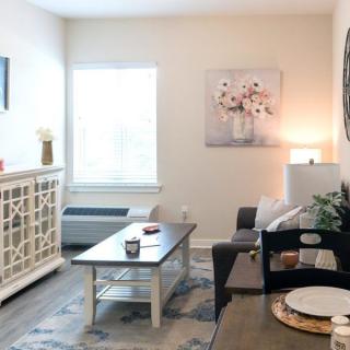 A cozy living room with modern dcor, featuring a sofa, coffee table, artwork, and soft lighting.