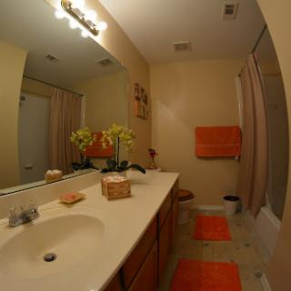 A well-decorated bathroom featuring a spacious vanity, orange towels, and floral decor.