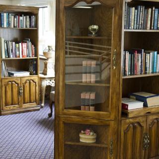 A cozy library room featuring wooden bookshelves filled with books and a display cabinet.