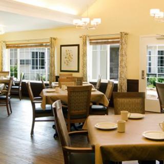 A well-lit dining area with neatly arranged tables and chairs, featuring large windows and elegant decor.