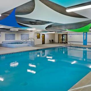 An indoor swimming pool with modern ceiling decorations and an adjacent hot tub.