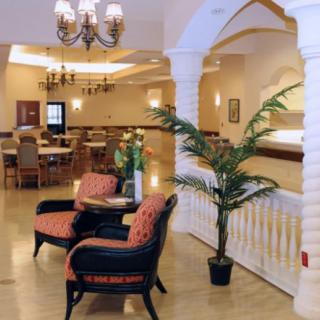 A well-decorated lobby with comfortable seating, elegant chandeliers, and a potted plant.