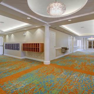 Spacious lobby with colorful carpet and elegant chandelier.