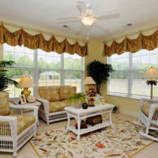 A cozy living room with wicker furniture and large windows.