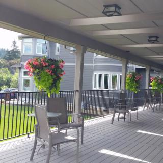 A sunny patio with tables, chairs, and vibrant hanging plants.