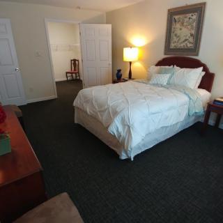 A cozy bedroom with a neatly made bed, nightstand, and lamp.