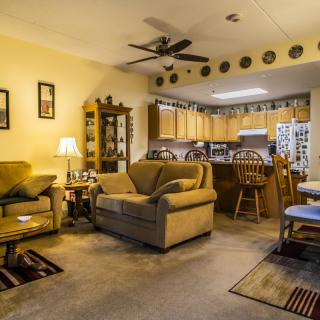 A cozy living room with an open kitchen, featuring comfortable seating and warm lighting.
