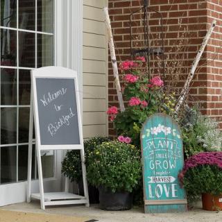 A welcoming outdoor scene with potted plants and charming signage.