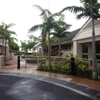 A suburban residential area featuring palm trees and a gated entrance.