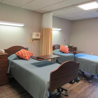 A spacious hospital patient room featuring two beds, equipped with bedside tables and comfortable pillows.