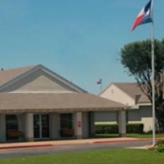 A building with a Texas flag waving under a clear blue sky.