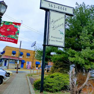 A view of a local business sign with colorful storefronts in the background.