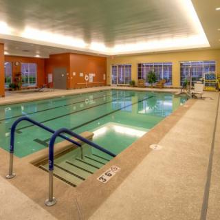 A spacious indoor swimming pool with surrounding deck chairs and large windows.
