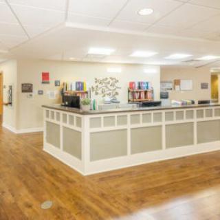 A spacious lobby with a reception counter and wooden flooring.