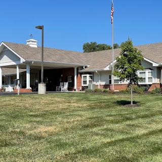 A sunny day at a care facility, showcasing the well-maintained lawn and welcoming entrance.