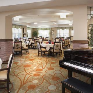 A well-decorated dining room with a grand piano and elegantly arranged tables.