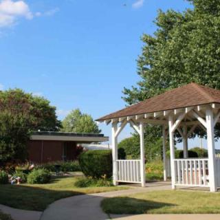 A peaceful garden setting with a wooden gazebo and lush greenery.