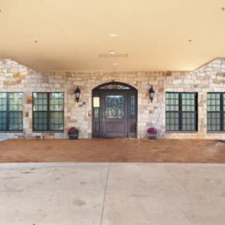 An elegant building entrance with a stone facade and arched wooden door.