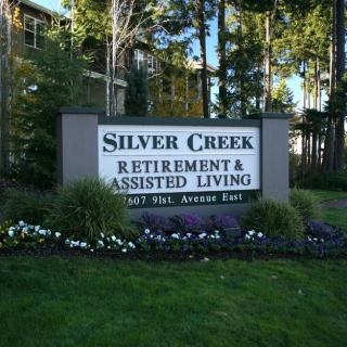Sign for Silver Creek Retirement & Assisted Living amidst a green landscape.