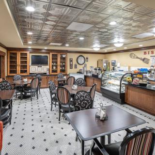 A cozy cafe interior with tables, chairs, and a display case.