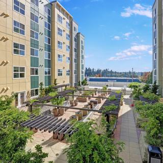 An outdoor courtyard area between apartment buildings featuring greenery and seating areas.