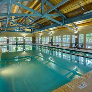 An indoor swimming pool with large windows and exposed ceiling beams.
