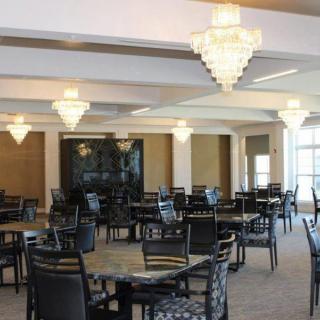 A spacious dining area with elegant chandeliers and neatly arranged tables and chairs.
