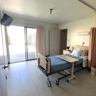 A bright and comfortable hospital patient room with a bed, window, and medical amenities.
