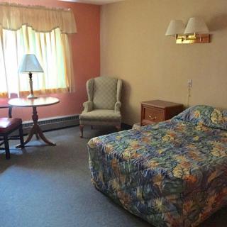 A cozy hotel room with a bed, armchair, and small table by the window.