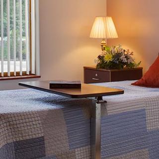 A cozy bedroom with twin beds, a bedside table lamp, and a small window.