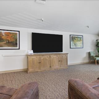 A cozy living room featuring comfortable seating, a large television, and tasteful wall art.