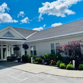 A well-maintained residential building with attractive landscaping under a blue sky with clouds.