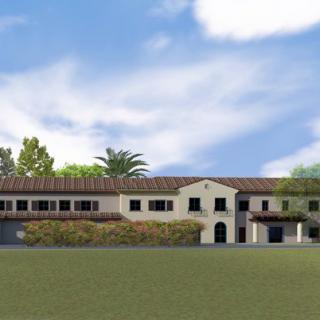 A scenic view of a large building with traditional architecture, set against a backdrop of trees and a cloudy sky.