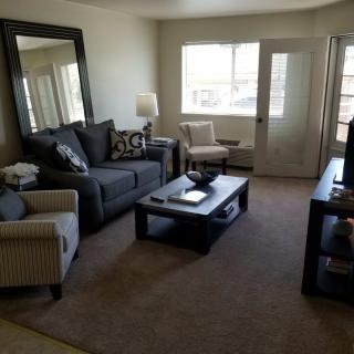 A cozy living room with a sofa, chairs, coffee table, and a large mirror.