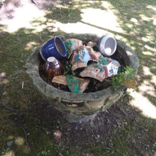 A trash can overflowing with various waste items in an outdoor setting.