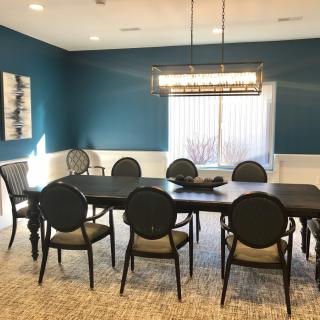 A modern dining room with blue walls, a large dining table, and elegant chairs.