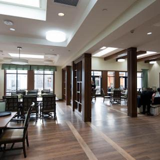 A spacious and modern community dining area featuring wooden floors and ample natural light.